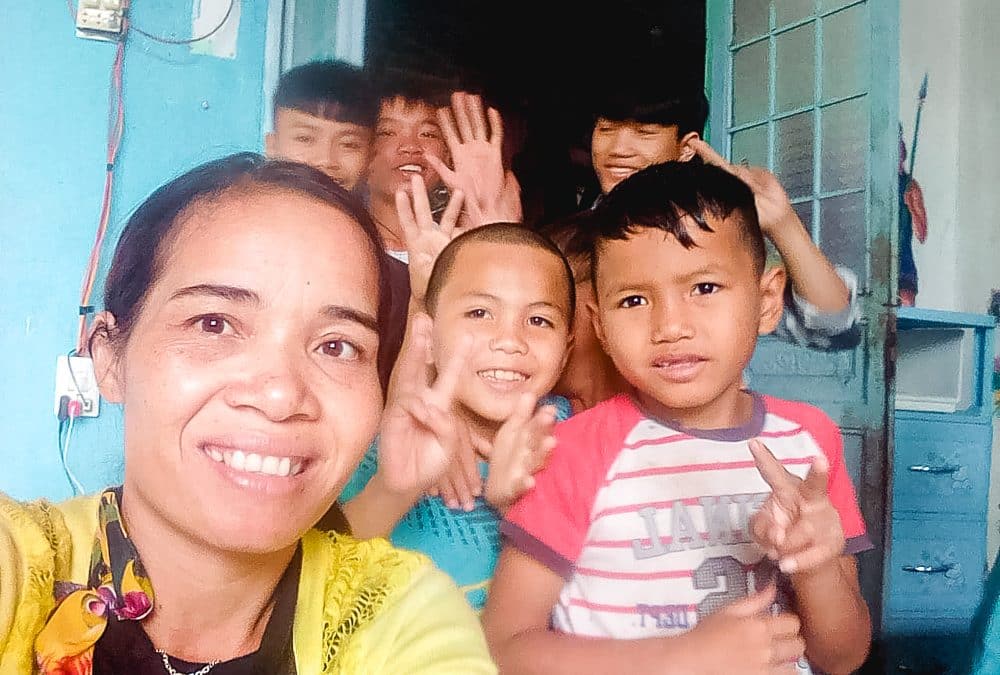 Vietnamese woman Teresa taking a photo with children in front of orphanage